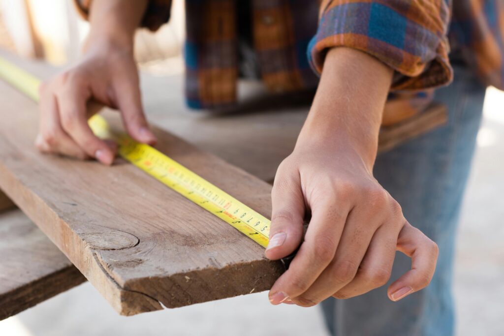 Apprentice carpenter measuring wooden beams